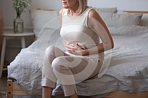 Sick mature woman hold belly feel abdominal ache in bed