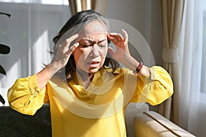 Sick mature woman touching her head suffering from head ache, migraine or dizziness. Age, medicine, health care and