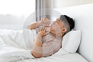 Sick middle aged asian man lying in bed and coughing