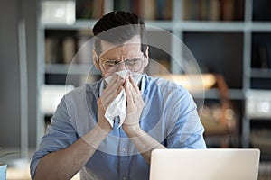Sick millennial unhappy businessman suffering from seasonal allergy.