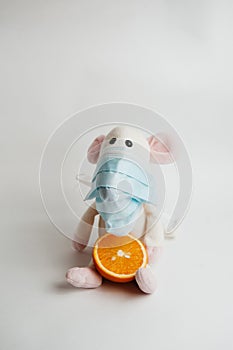 Sick mouse in a mask with an orange on a white background