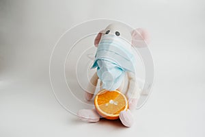 Sick mouse in a mask with an orange on a white background