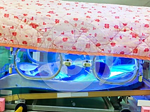 Sick newborn baby sleeping in phototherapy unit box for treatment neonatal hyperbilirubinemia and neonatal jaundice in NICU wards photo