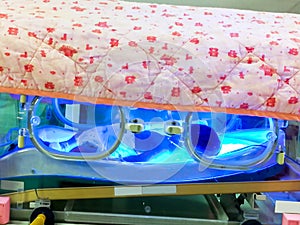 Sick newborn baby sleeping in phototherapy unit box for treatment neonatal hyperbilirubinemia and neonatal jaundice in NICU wards