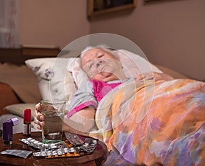Sick old woman lying in bed at home