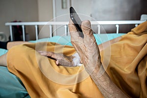 Sick old woman under inpatient treatment in hospital contacting family using smartphone