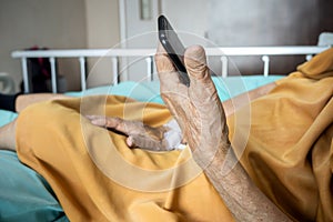 Sick old woman under inpatient treatment in hospital contacting family using smartphone