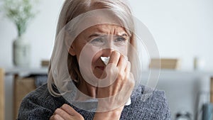 Sick older woman blowing nose close up, holding handkerchief