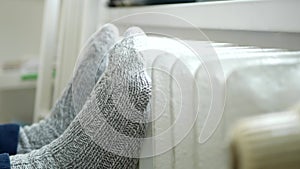 Sick Person at Home Sitting and Warming His Feet on a Heating Radiator.