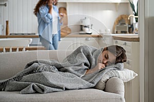 Sick repressed teen girl sleeping in house on couch wrapped in blanket warming up in cold weather photo