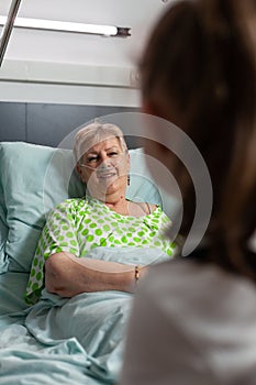 Sick retired grandmother talking with grandchild while resting in bed