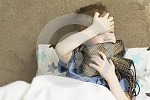 Sick sad child in temperature and headache lies in bed. Flu colds disease virus