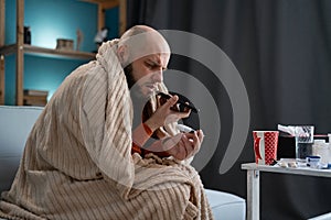 Sick sad man in blanket dictate voice message on smartphone at home. Health, cold and people