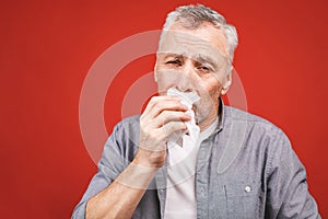 Sick senior man blowing his nose with tissue. having flu, aller