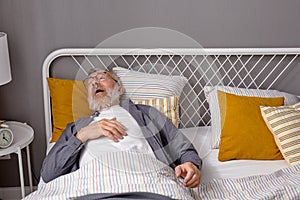 Sick senior man is going to sneeze while lying on bed