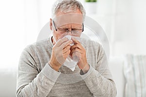 Sick senior man with paper wipe blowing his nose