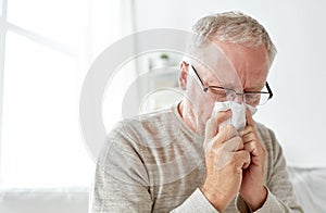 Sick senior man with paper wipe blowing his nose