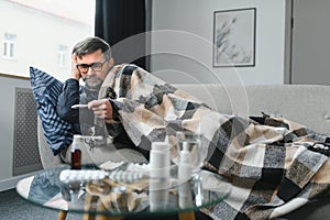 Sick senior man using thermometer checking his temperature suffering from seasonal flu or cold.