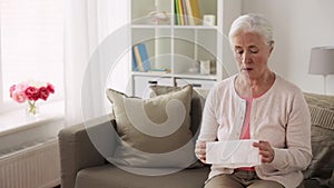 Sick senior woman blowing nose to paper napkin