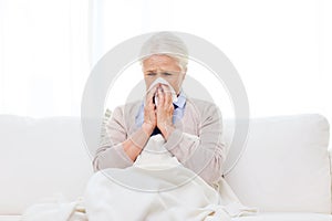 Sick senior woman blowing nose to paper napkin photo