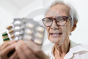 Sick senior woman holding medicine pills or capsules,sad female elderly showing a lot of drugs,treatment,medication to reduce pain