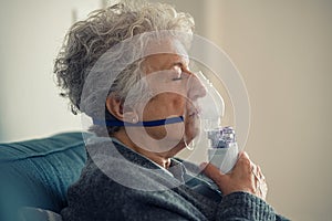 Sick senior woman making inhalation with nebulizer