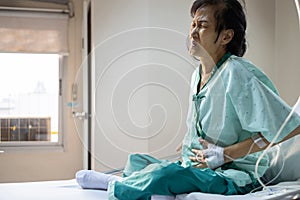 Sick senior woman suffering from appendicitis,severe abdominal pain,female patient with a stomach ache sit in a hospital bed,
