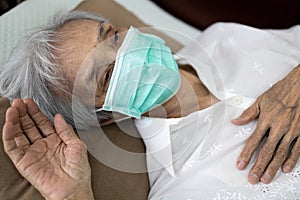 Sick senior woman wear a mask lying in uncomfortable bed,unwell,exhausted old people have a fever,cold and flu,tired elderly