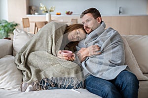 Sick sleepy woman feeling unwell, having high temperature, leaning on man shoulder with cup of tea