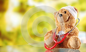 Sick Teddy Bear with Stethoscope on Glass Table