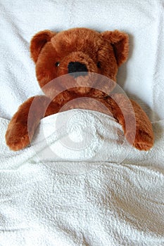 Sick teddy with injury in bed