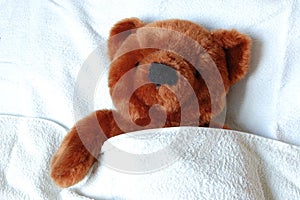 Sick teddy with injury in bed