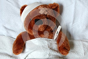 Sick teddy with injury in bed