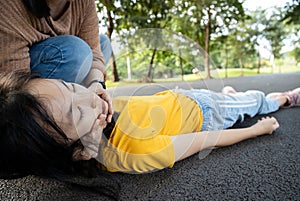 Sick teen daughter is fainted and fallen on floor while playing at park,asian mother help,take care,child girl with congestive photo