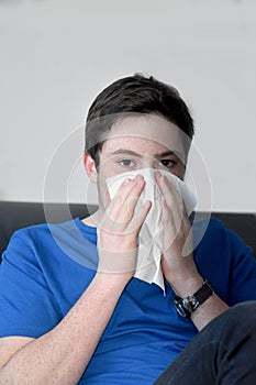 Sick teenage boy blowing his nose
