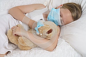 A sick teenage girl is playing with a toy wearing a protective mask
