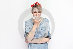 Sick unhealthy blonde woman standing suffering runny nose, having grippe symptoms.