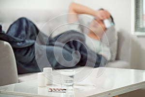 sick wasted man lying in sofa having medicine tablets
