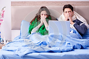 The sick wife and husband in bed with laptop