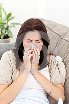 Sick woman blowing her nose on the sofa