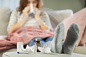 Sick woman blowing her nose with a tissue at home