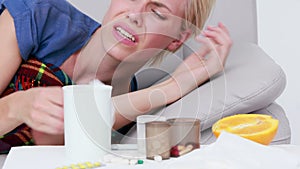 Sick woman blowing his nose while she is lying on bed