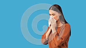 Sick Woman Blowing Runny Nose In Paper Tissue, Blue Background