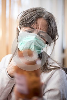 Sick woman of corona wears a protective mask, with a container of medicine