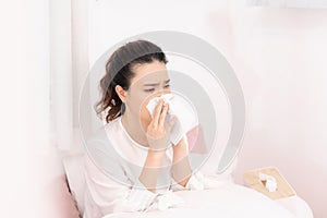 Sick woman covered with a blanket lying in bed with high fever and a flu, resting