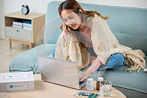 sick woman covered blanket suffering from virus but still working at home with laptop computer