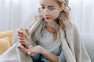 Sick woman covered with blanket take pill