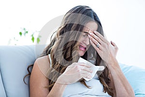 Sick woman crying on sofa