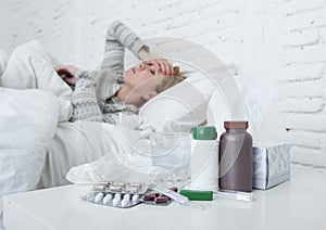 Sick woman feeling bad ill lying on bed suffering headache winter cold and flu virus having medicines