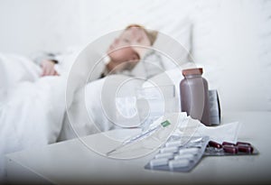 sick woman feeling bad ill lying on bed suffering headache winter cold and flu virus having medicines